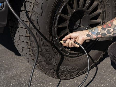 guy with a tattoos inflating a tire