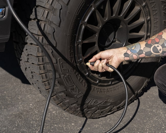 guy with a tattoos inflating a tire